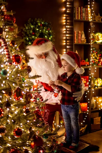 Jultomten dekorera julgran med liten pojke assistent hemma. Nytt år, lycklig barndom — Stockfoto