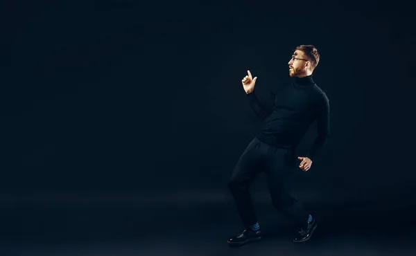 Полная длина смешной хипстер парень в черном исполнительский танец шоу, который изолирован на черном фоне. — стоковое фото