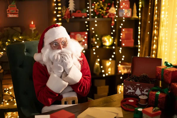 Emotionaler Claus sitzt zu Hause am Tisch und liest Briefe mit Wünschen — Stockfoto