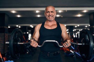  Spor salonundaki pazılarda halterle egzersiz yapan yaşlı vücutçunun ön görüntüsü. Vücut geliştirme kavramı