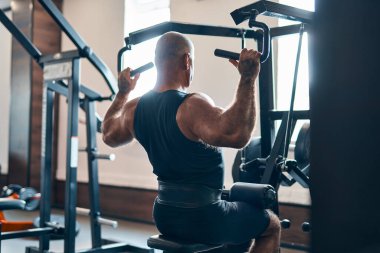 Yetişkin vücut geliştirici beden eğitimi dersinde makinede ağırlık egzersizi yapıyor. Vücut geliştirme kavramı