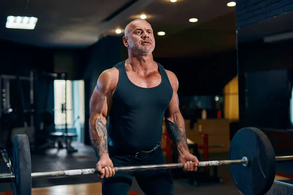 Дорослий сильний атлетичний чоловік підкачує м'язи біцепсів під час тренувань у спортзалі. концепція бодібілдингу — стокове фото