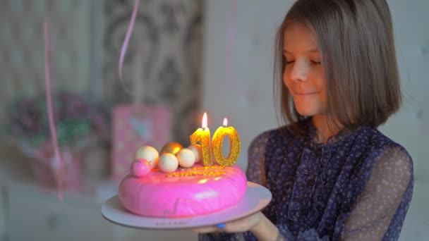 Roztomilá šťastná mladá dívka si něco přeje a sfoukne svíčky na narozeninovém dortu na párty. Dovolená. 10 let — Stock video