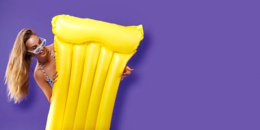 Sarı şişme şilteli, mor stüdyo geçmişli, bikinili komik kız anket yapacak.