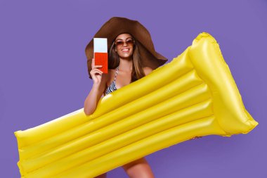 Güneş şapkalı mutlu kız seyahate çıkıyor. Sarı şişme şilteli, biletli, pasaportlu.