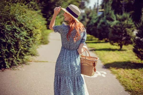 Hátsó kilátás felnőtt vidám lány stílusos szalma táska és szalma kalap, aki sétál a parkban szabadban — Stock Fotó
