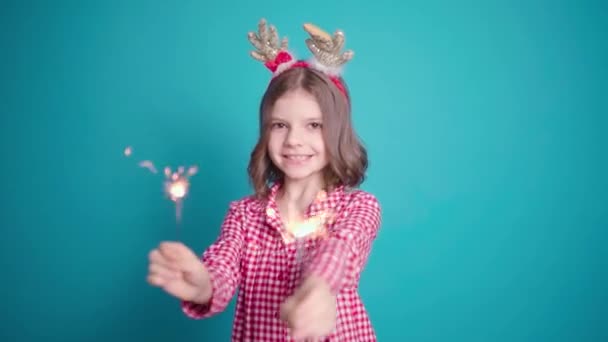 Heureuse petite fille regardant avec admiration à la combustion scintillant dans sa main sur fond bleu — Video