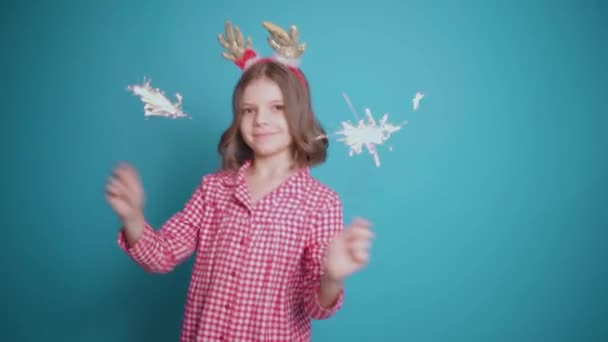 Gelukkig klein meisje op zoek met bewondering op branden schittering in haar hand over blauwe achtergrond — Stockvideo