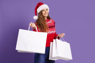 Mor arka planda alışveriş torbaları tutan mutlu kız. Noel hediyeleri. Noel satışları. Kara Cuma