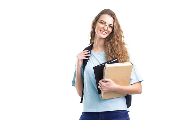 Sorridente studentessa tiene libri mentre guarda la fotocamera. Su sfondo bianco. Istruzione. — Foto Stock