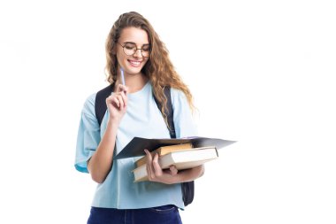 Gülümseyen öğrenci kız deftere bakarken kalem ve kitap tutuyor. Eğitim kavramı 