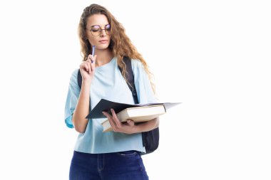 Düşünceli öğrenci kız deftere bakarken kalem ve kitap tutuyor. Eğitim kavramı 