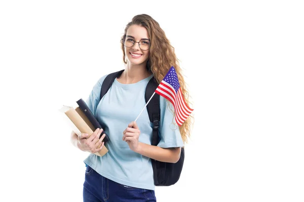 バックパック付きの笑顔の若い学生の女性は白い背景に本、ノートブック、フラグUSAを保持 — ストック写真