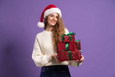 Noel kadınının elinde mor stüdyo arka planında bir sürü hediye kutusu var. Noel konsepti. Satışlar 