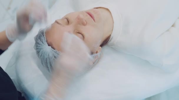 Kosmetikerin entfernt mit speziellen Feuchttüchern Reste eines kosmetischen Gesichtsproduktes vom weiblichen Gesicht — Stockvideo