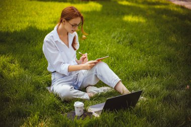 Güzel kız laptopla, blogcuyla, evde, açık havada okuyor ve çalışıyor.