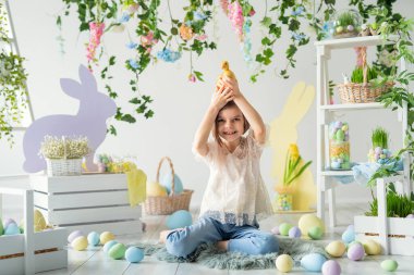 Neşeli kız yerde otururken ördek yavrusuyla iletişim kuruyor. Paskalya dekorasyonu. 