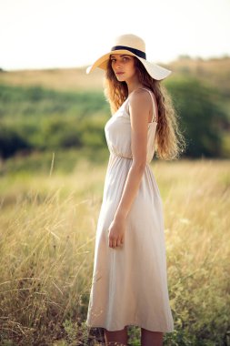 Güneş şapkalı ve açık havada dolaşan romantik elbiseli çekici beyaz kız. Moda Yaşam Tarzı