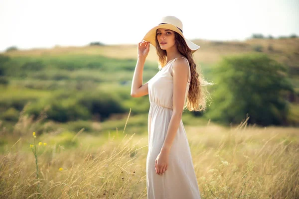 Jeune jolie femme se promène sur le terrain en été tout en portant un chapeau de soleil et robe midi. Mode de vie — Photo