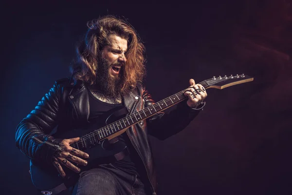 Guitar player. Rockstar bearded man emotional plays on guitar isolated on black background. — Stockfoto