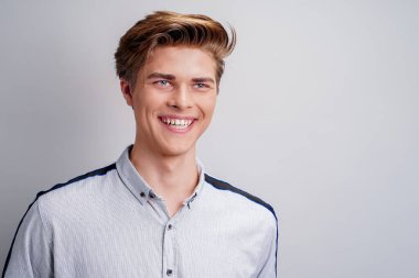  Yakışıklı genç adam kameraya bakarken mükemmel bir gülümsemeyle gömlek giyiyor. Şık saç stili. 