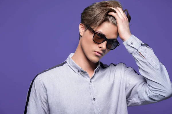 Male hairstyle concept. Hipster guy with stylish haircut in sunglasses stands over lilac background. — Stock Photo, Image