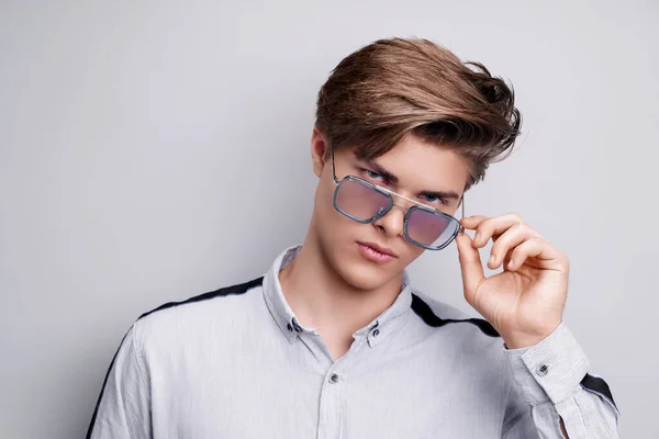 Akcesoria męskie, optyka. Hipsterski młodzieniec w koszuli i nowoczesnych okularach przeciwsłonecznych. Portret studenta — Zdjęcie stockowe