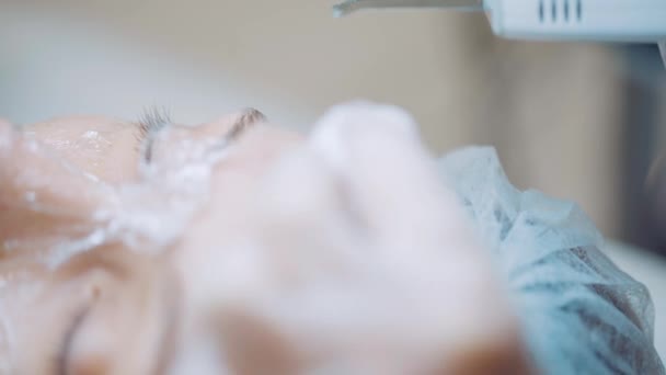 Junge Frau lässt sich von Kosmetikerin kometologisch behandeln. Professionelle Ultraschall-Gesichtsreinigung — Stockvideo