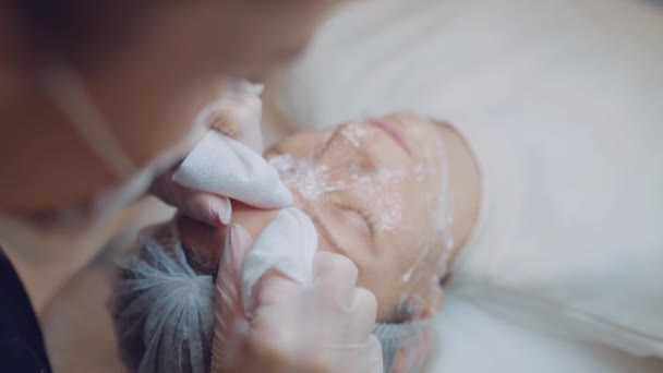 Top view handen van cosmetoloog die het gezicht vrouwelijke patiënt van acne reinigt. huidverzorging. Gezicht schoon — Stockvideo
