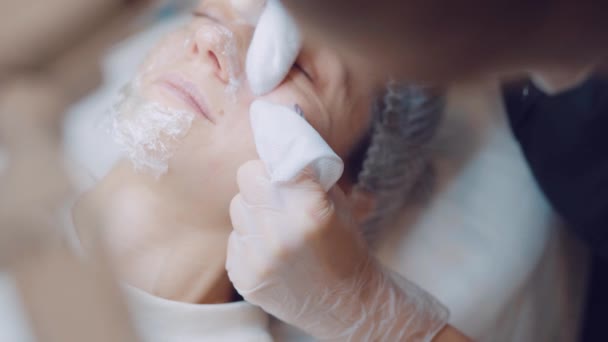 Mladá žena na kosmetické klinice uklízí obličej. Profesionální péče o pleť. Čištění rukou na obličeji — Stock video
