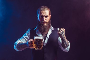 Duygusal sakallı adam el kol hareketi yaparken bir kupa lezzetli bira tutuyor. Ekim festivali konsepti