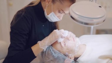 Güzellik uzmanı kızın yüzünü elleriyle temizliyor..