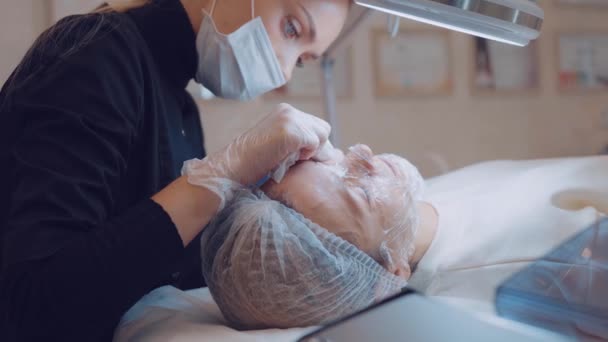 Visão lateral do cosmetologist Feminino faz à limpeza facial paciente por mãos. Cuidados com a pele profissional — Vídeo de Stock