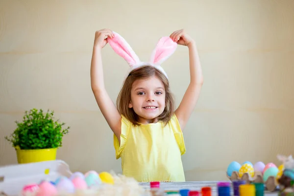 Śmieszne przygotowania do Wielkanocy. Wielkanoc malowane jaja. Słodkie dziecko dziewczyna nosi króliczki uszy. Koncepcja wielkanocna — Zdjęcie stockowe