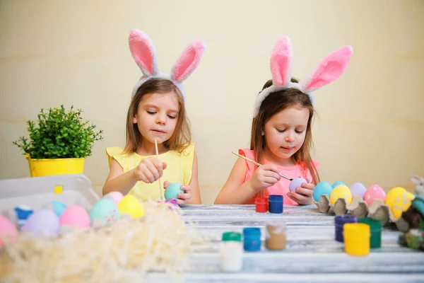 Dzieci w uszach króliczków malować i dekorować pisanki. Przygotowania do Wielkanocy — Zdjęcie stockowe