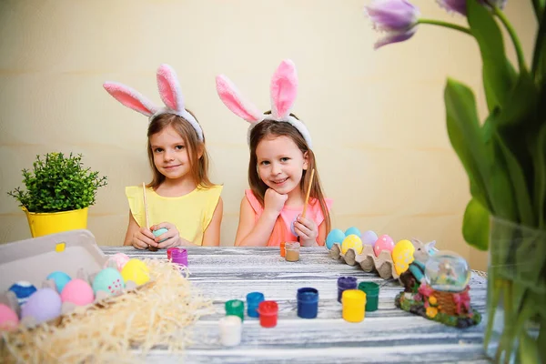 Dwie słodkie dziewczynki w króliczki uszy malować i dekorować pisanki. Przygotowania do Wielkanocy — Zdjęcie stockowe