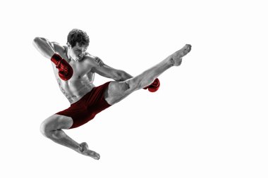 Stüdyo siluetinde Muay Thai dövüş sanatları icra eden tam boy bir boksör. Kırmızı spor giyim. 