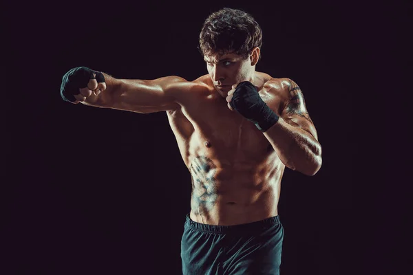 Retrato de boxeador agresivo que entrena y practica jab sobre fondo negro. Concepto deportivo — Foto de Stock