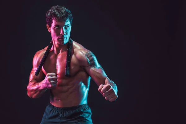 Media longitud de atleta masculino fuerte que posa con nunchaku sobre fondo negro. Concepto deportivo — Foto de Stock