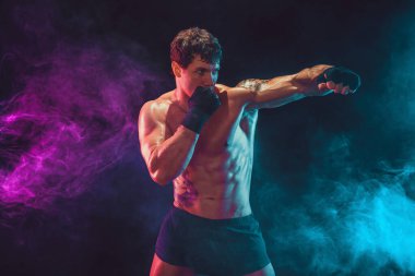 Duman arka planında antrenman yapan ve salıncakta sallanan boksör. Spor konsepti