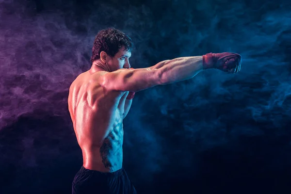 煙の背景にジャブを訓練し、練習積極的なボクサーの側面図。スポーツコンセプト — ストック写真