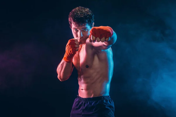 Vista frontal de boxeador agresivo que entrena y practica jab sobre fondo de humo. Concepto deportivo — Foto de Stock