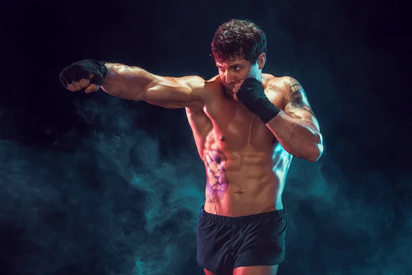 Половина мускулистого боксера, который тренируется и практикует джеб на дымовом фоне. Концепция — стоковое фото