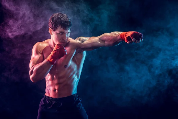Портрет агрессивного боксера, который тренируется и практикует джеб на дымовом фоне. Концепция — стоковое фото