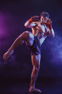 Diz vuruşu yapan Muay Thai savaşçısının tam boyutu duman arka planında izole edildi. karışık ortam 