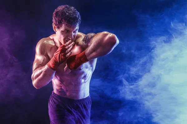 Retrato de kickboxer musculoso que entrega el codo golpeado aislado sobre el fondo de humo. Medios mixtos — Foto de Stock