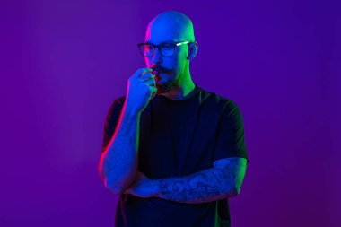 Genç kel adam elektronik sigara kullanıyor, stüdyoda sigara içiyor. Renk filtreleri. Vaping konsepti