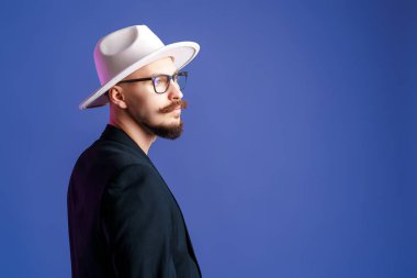  Beyaz kenarlı şapkalı ve ceketli şık sakallı adamın yan görünüşü..