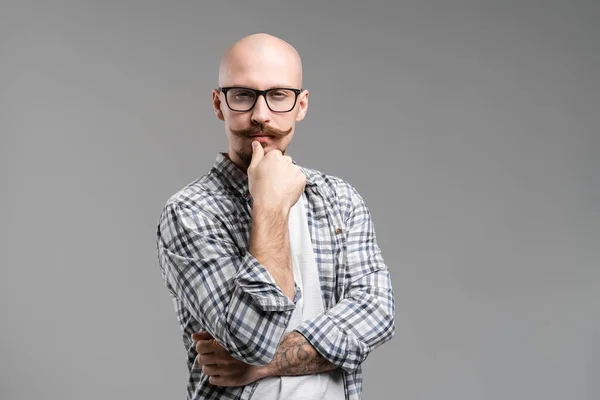 Vorderansicht eines denkenden bärtigen Mannes mit Brille, der die Faust auf dem Kinn hält, isoliert auf grauem Hintergrund — Stockfoto