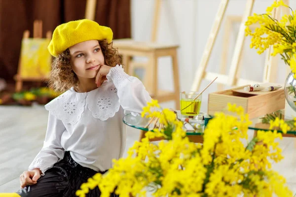 Маленька мила кучерява дівчинка в жовтому береті і колготках, яка позує в студії — стокове фото